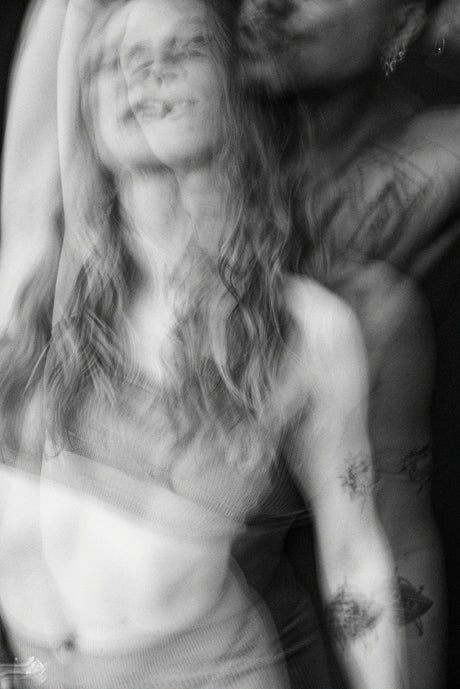 A blurred black and white photo of a person with tattoos, captured in motion.